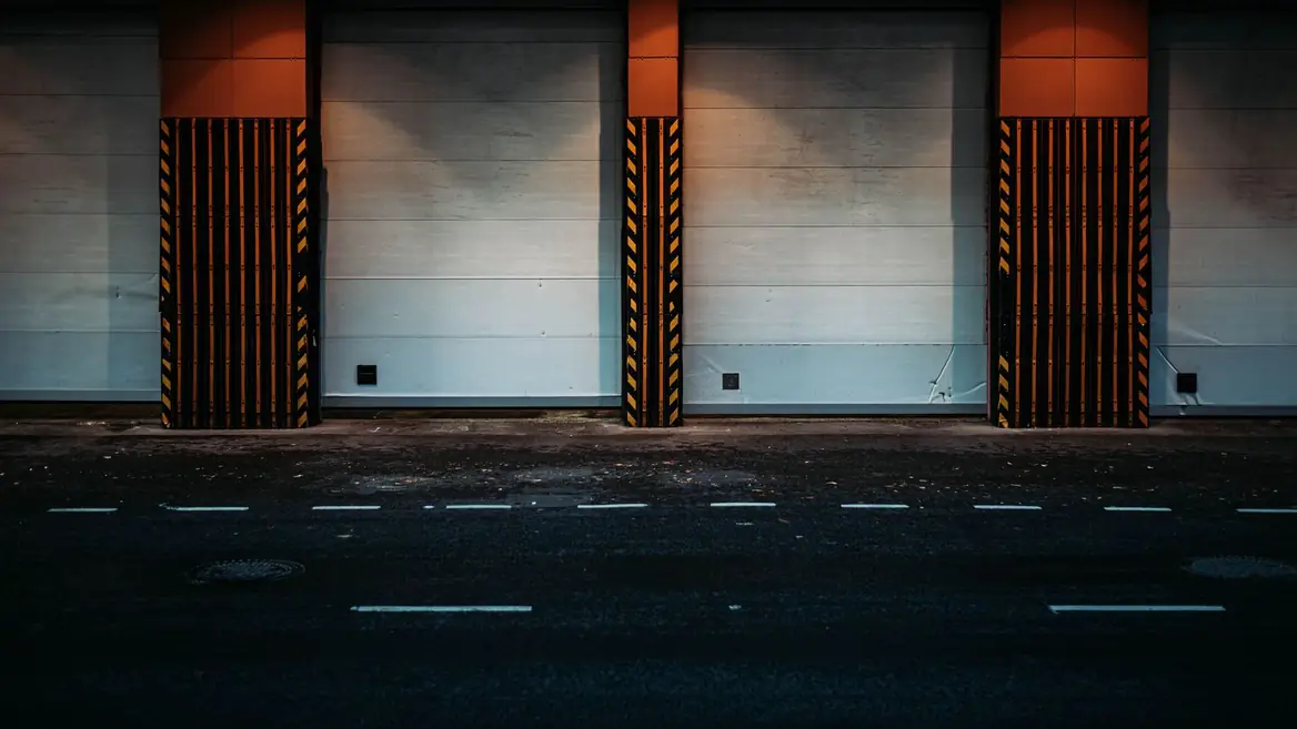 Three shuttered loading bays at night, each edged with black and yellow hazard stripes.
